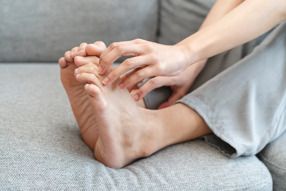 Eine Person auf einer Couch liegend hat die Fingernägel auf den nackten Füssen angelegt