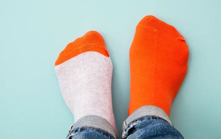 Füsse in unterschiedlichen Socken, die eine rot, die andere grau mit roter Spitze