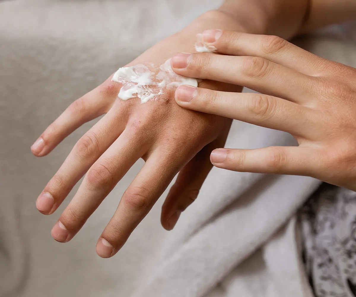 Eine Hand verteilt größzügig Creme auf dem anderen Handrücken