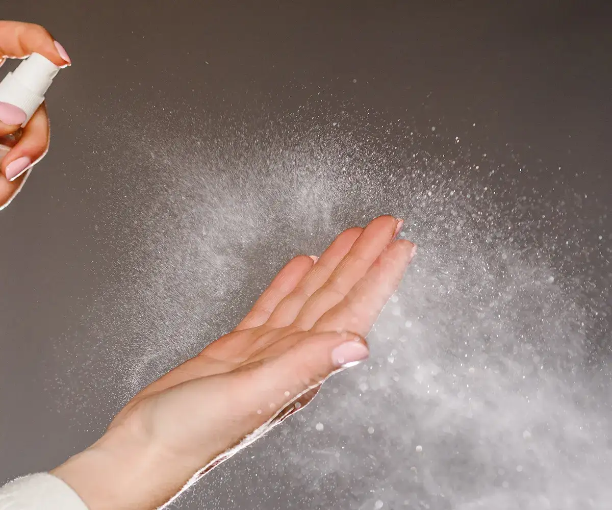 Spray wird auf einer Hand angewendet