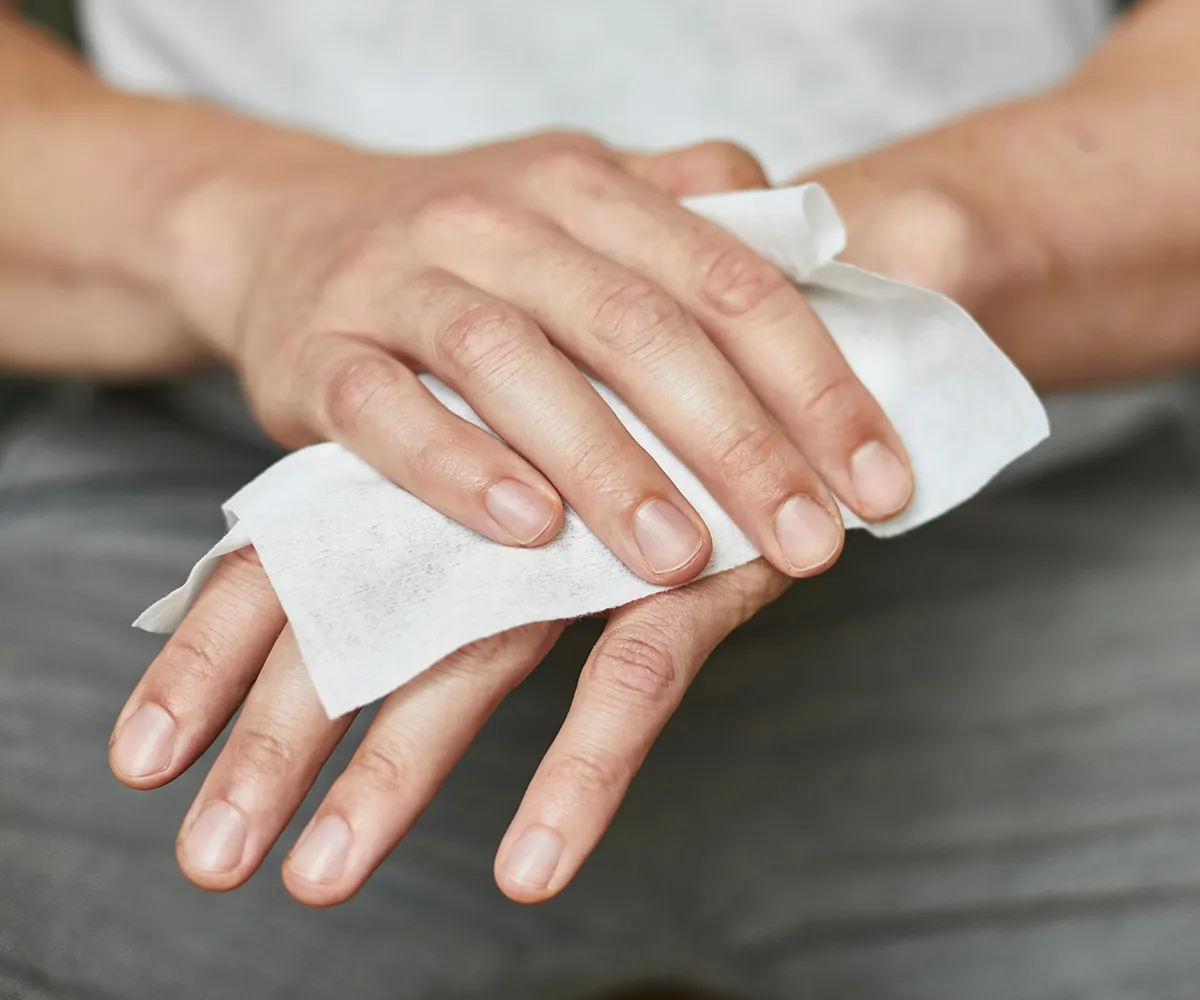 Pilzinfektion Hautpilz Regelmäßige Hygiene Eine Hand wischt bei der anderen den Handrücken mit einem Tuch ab