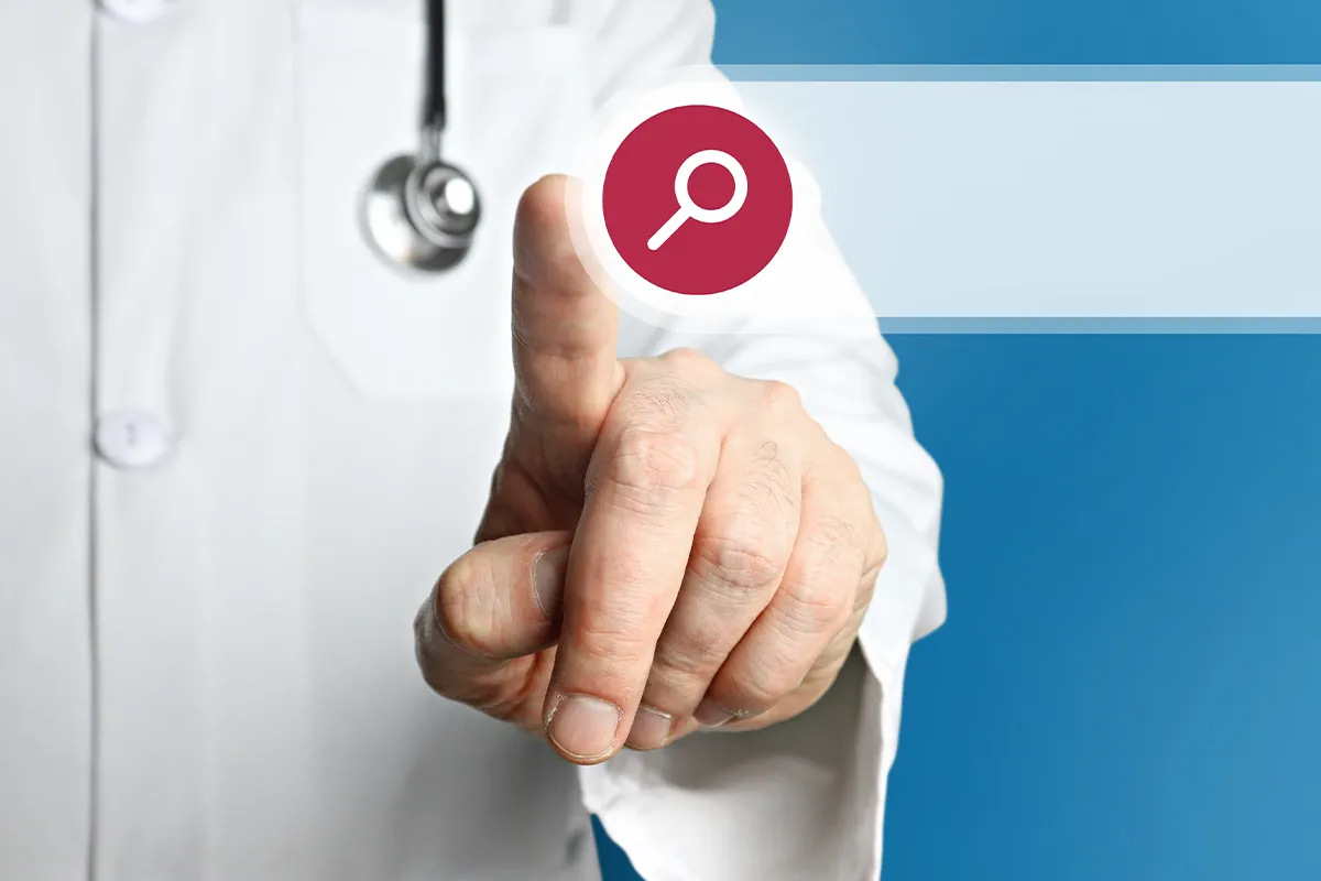 Eine männliche Person im Kittel und Stetoskop um zeigt auf eine Fläche, die wie eine Suchfeld im Internet aus sieht