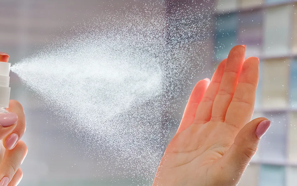 Spray wird auf einer Hand angewendet