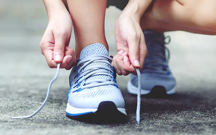 Jemand hat die Hände zum schnürren seiner Laufschuhe angesetzt