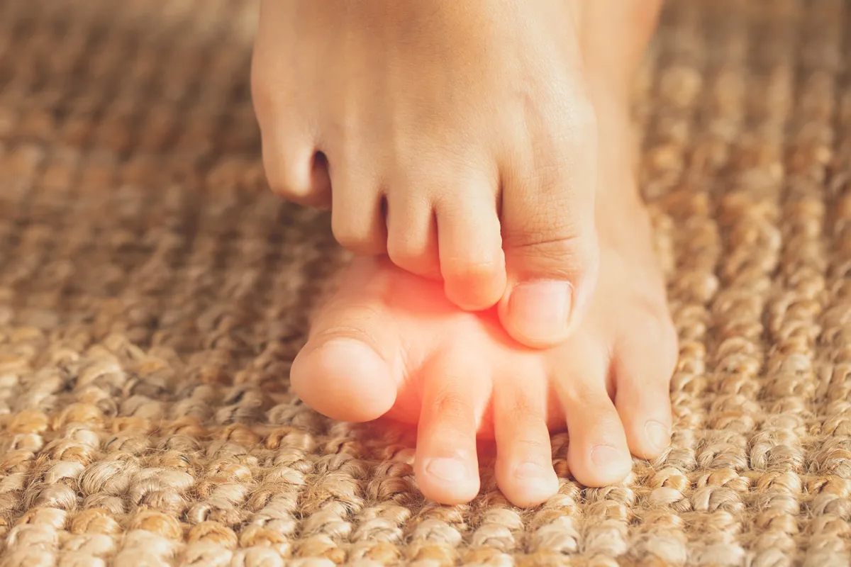 Ein Fuss liegt auf einem anderen mit den Zehen auf und darunter sind schemenhaft rot markierte Bereiche