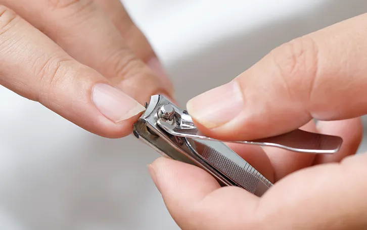 Nagelknipser Nahaufnahme in Händen beim stutzen von einem Fingernagel